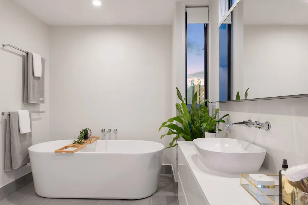 Modern white bathroom with freestanding soaking tub, vessel sink, and large window showing semi-gloss paint finish