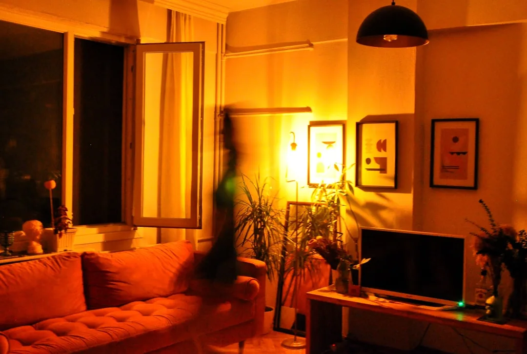 Living room with warm amber lighting from floor lamp showing yellow-orange color cast on walls and furniture