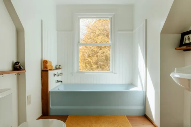 Light blue bathtub in white beadboard bathroom wit