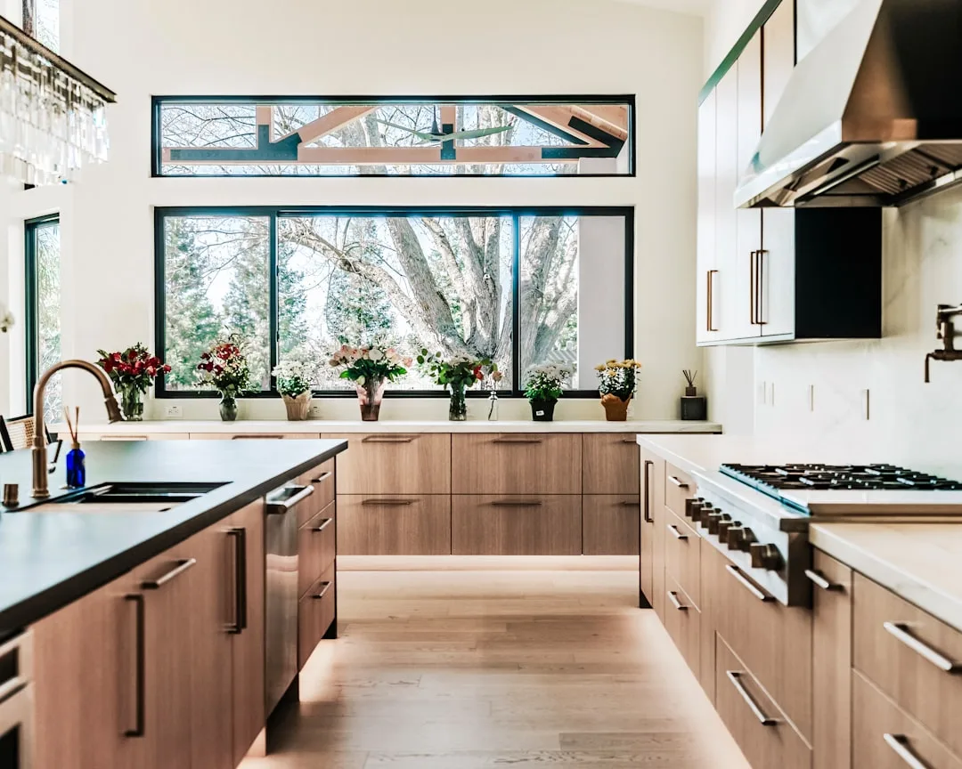 Modern custom kitchen with flat-panel wood cabinets, white quartz countertops, and large garden windows