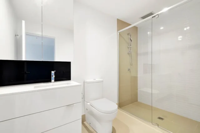 Modern white bathroom with glass shower enclosure,