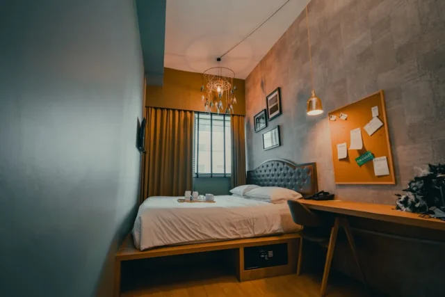Small hotel bedroom with queen bed on wooden platf