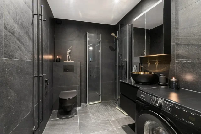 Dark moody bathroom with black tiles, wall-hung to