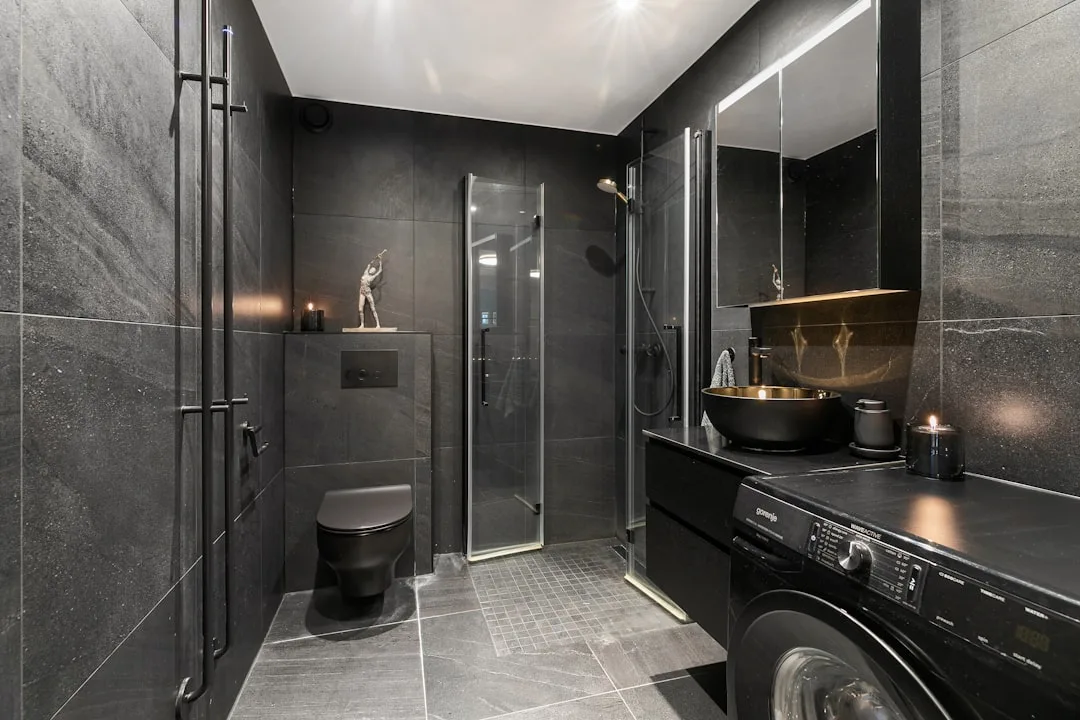 Dark moody bathroom with black tiles, wall-hung to