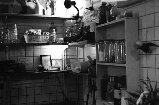 Cluttered open kitchen shelves with jars, bottles,
