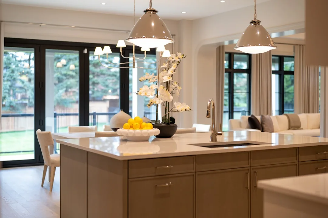 Modern kitchen island with sink, pendant lights, and white quartz countertop in open-plan luxury kitchen