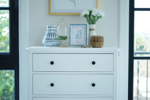 White dresser with black knobs styled with blue an