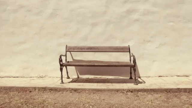 Lone wooden park bench with ornate iron legs again