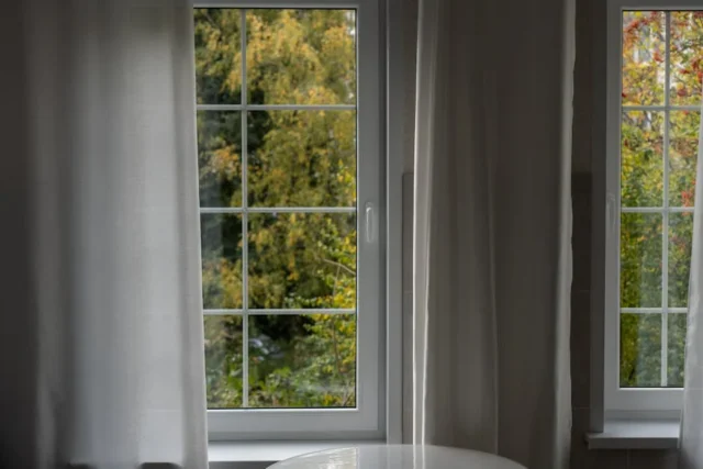 White-framed windows with sheer curtains overlooki