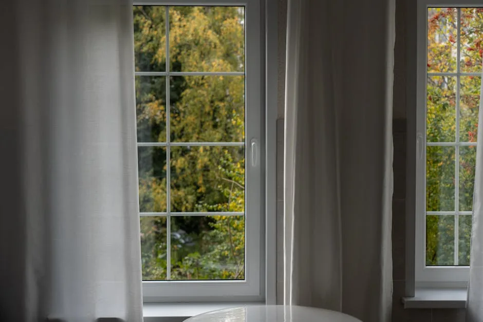 White-framed windows with sheer curtains overlooki