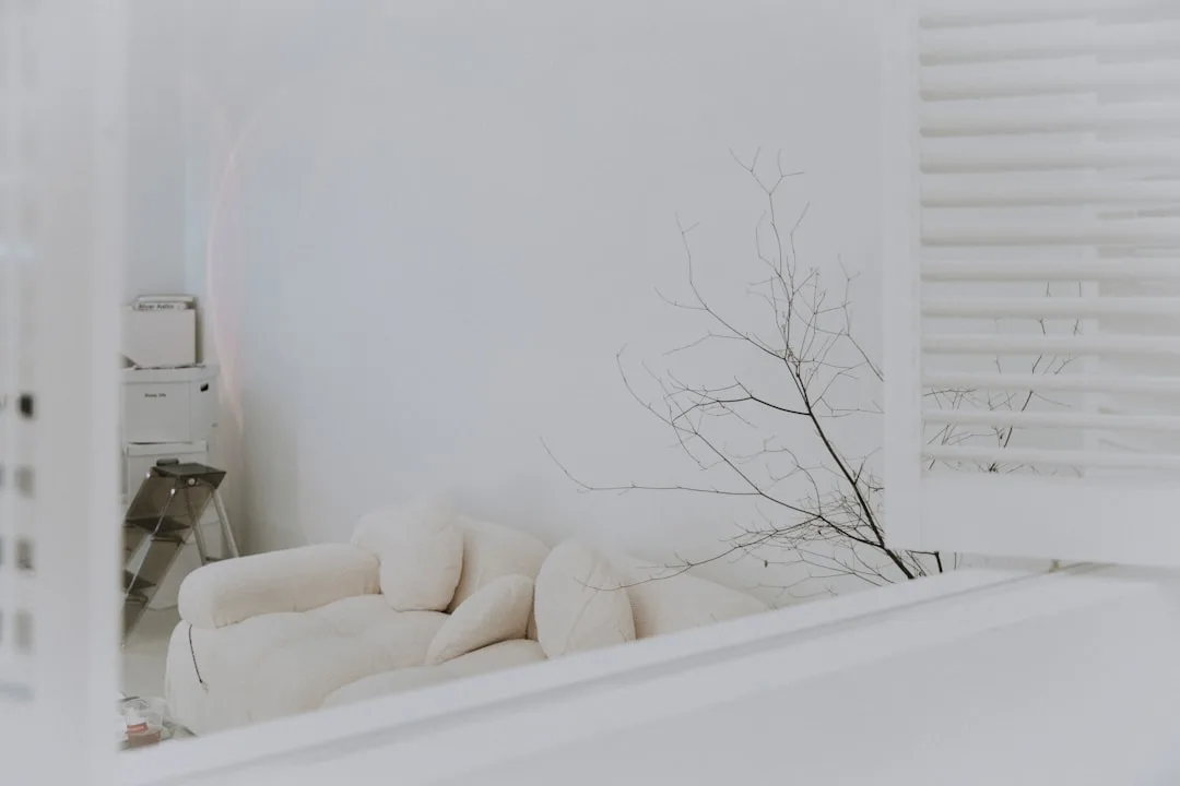 Minimalist white interior with cream boucle sofa and bare branch decor showing warm white tones in a bright room