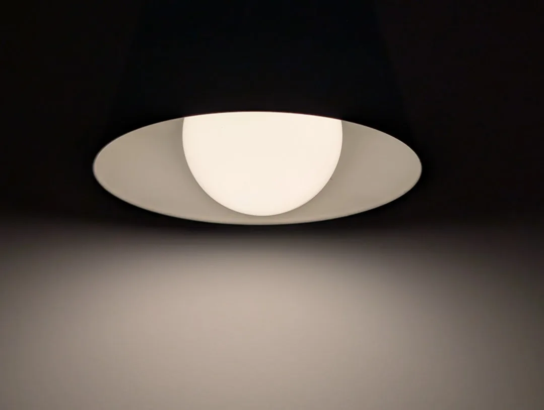 Modern recessed ceiling light fixture with opal globe diffuser casting warm ambient glow on wall below