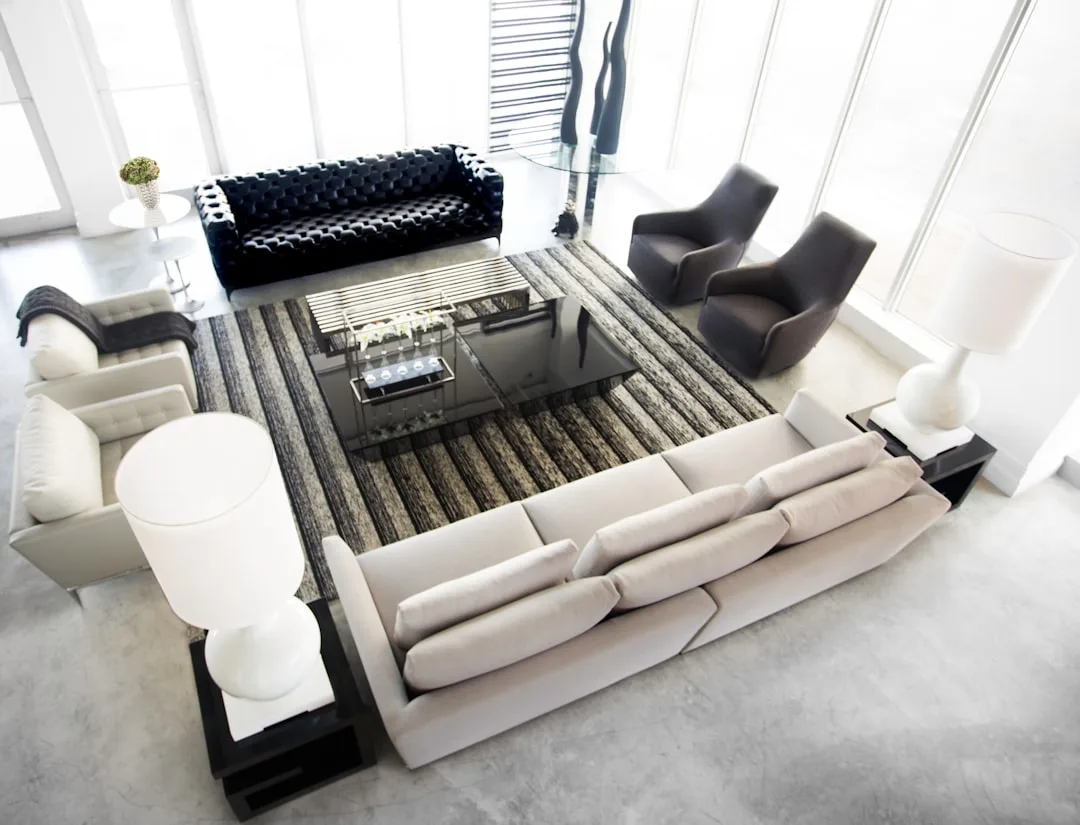 Oversized white sofa paired with slim black tufted two-seater in modern monochrome living room with scale contrast