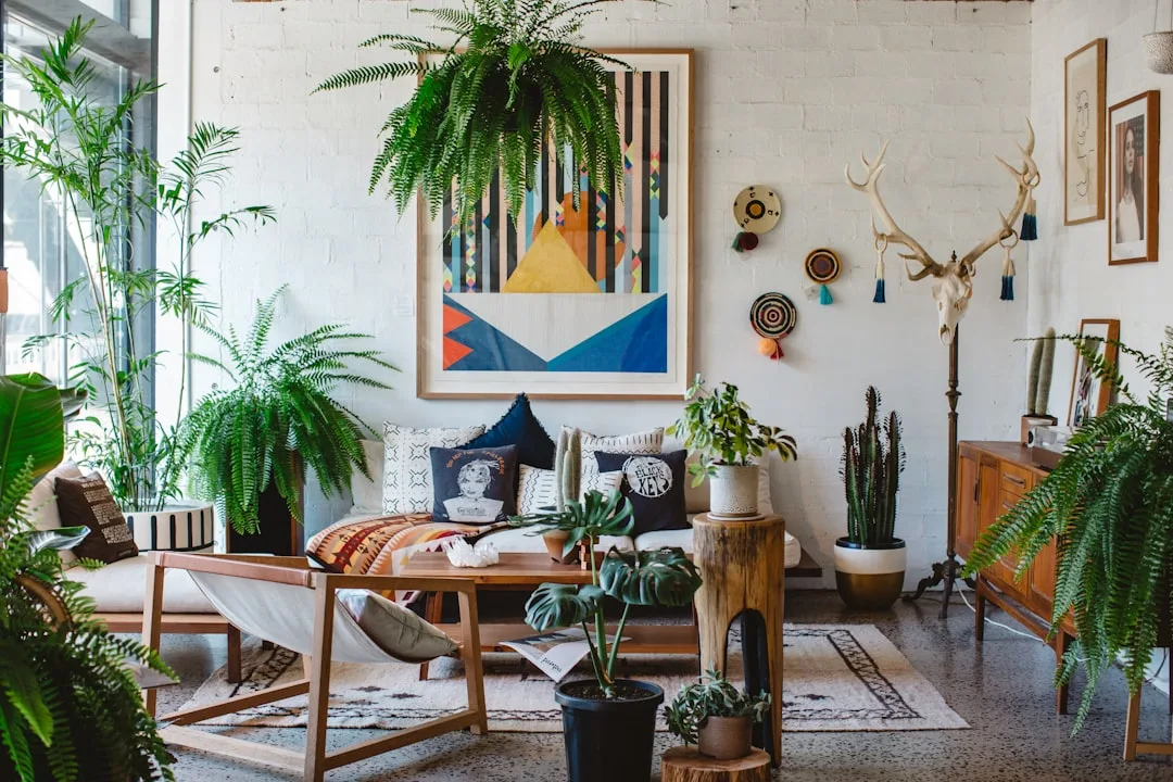 Bohemian living room with lush ferns, monstera, cacti, natural wood furniture, and eclectic wall art on white brick
