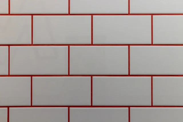 White subway tiles with bold red grout showing hig