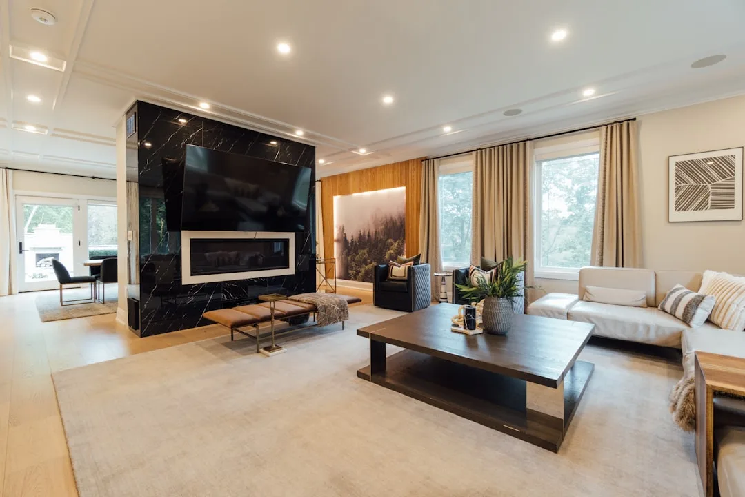 Modern living room with floor-to-ceiling curtains on large windows beside black marble fireplace wall