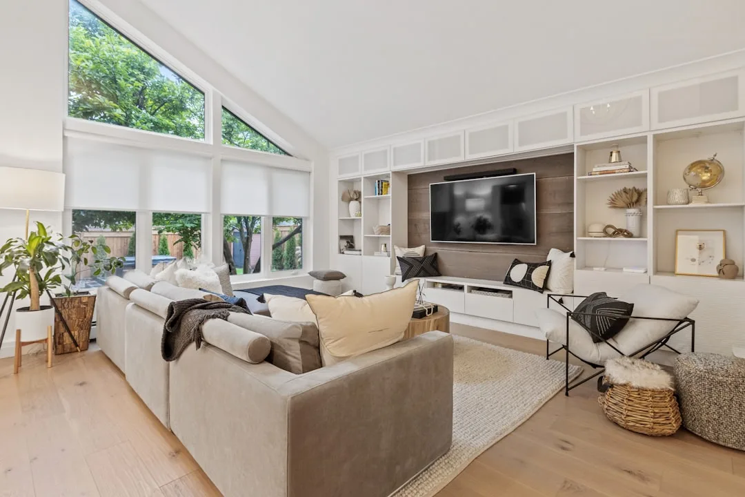 TV mounted on wood accent wall in modern living room with built-in shelving and sectional sofa at proper eye-level heigh