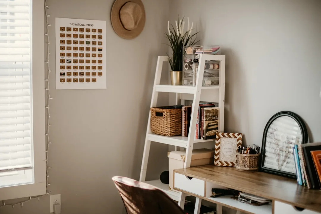 White ladder shelf with books and basket beside a wooden desk in a cozy bedroom workspace corner