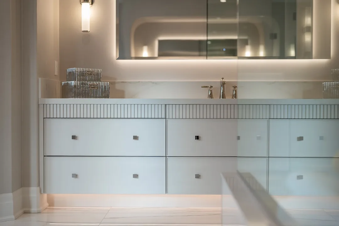 Modern bathroom vanity with white drawers, backlit mirror, and marble countertop for bathroom storage inspiration