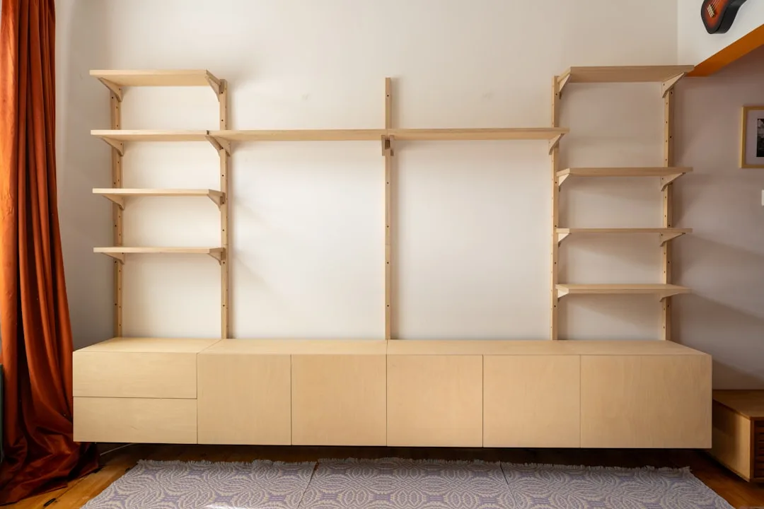Custom birch plywood wall-mounted shelving system with lower cabinet storage unit in a modern living room