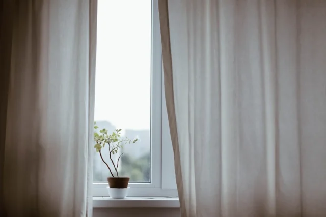White linen curtains hanging floor-length beside a