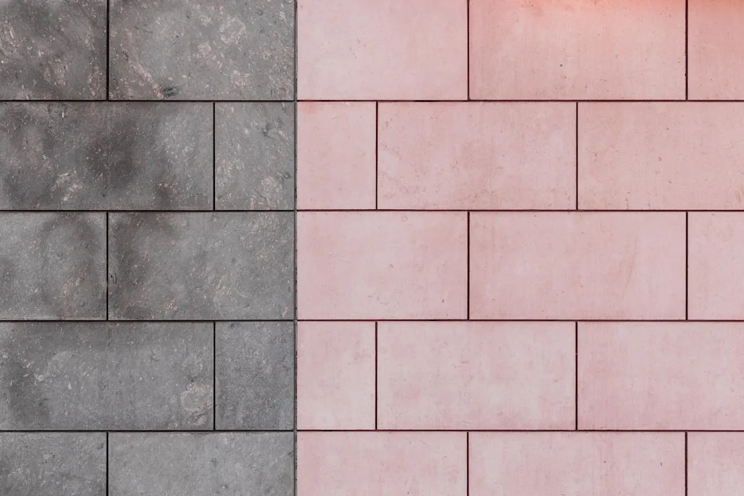 Side-by-side comparison of gray and pink rectangular tiles on an accent wall showing texture and color contrast
