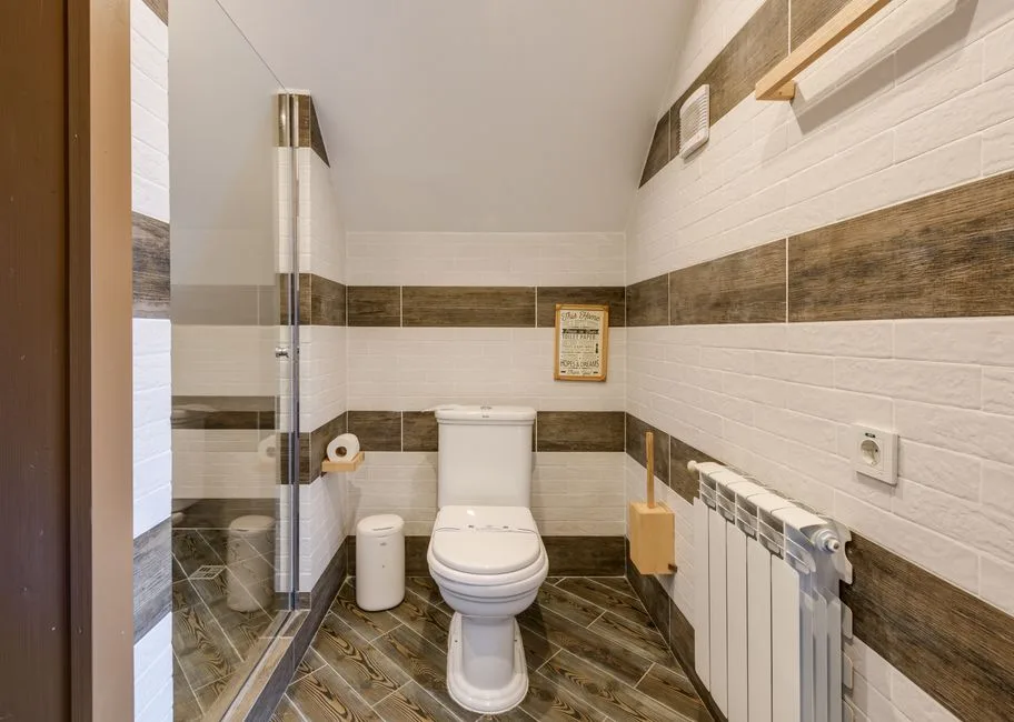 Compact bathroom with wet room shower enclosure, toilet, and wood-effect tiles showing small space wet room layout
