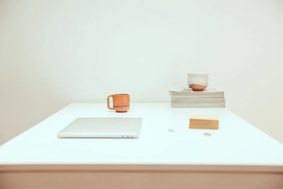 Minimalist white desk with closed laptop, ceramic