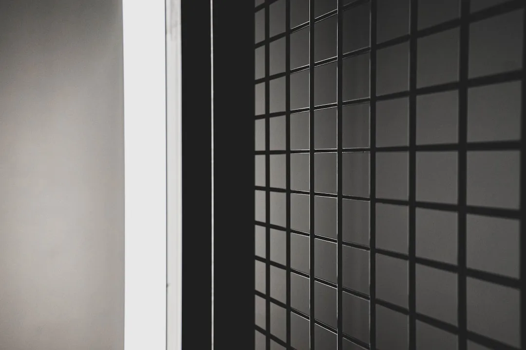 Close-up of black square wall tiles with dark grout lines showing depth and pattern in a modern interior