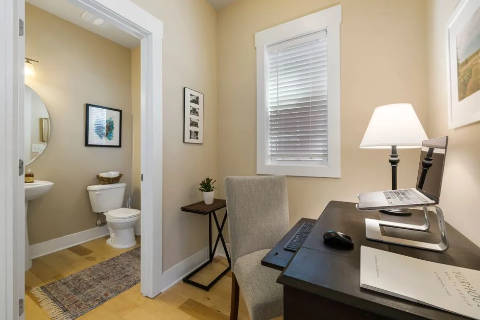 Home office and bathroom zones separated by open doorway showing two distinct functional areas in one small space